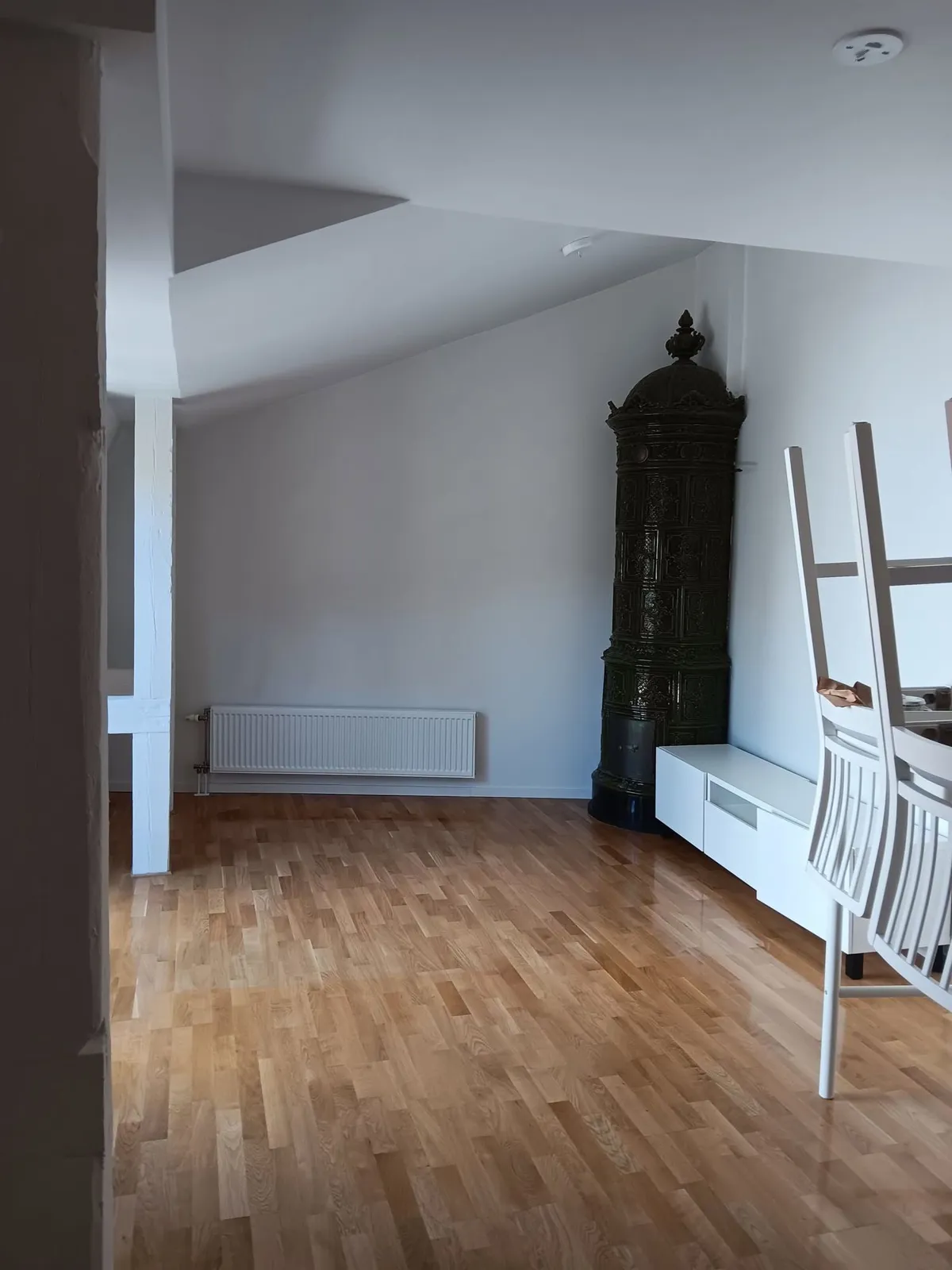 Vardagsrum med ekparkett, kakelugn och snedtak efter flyttstädning
